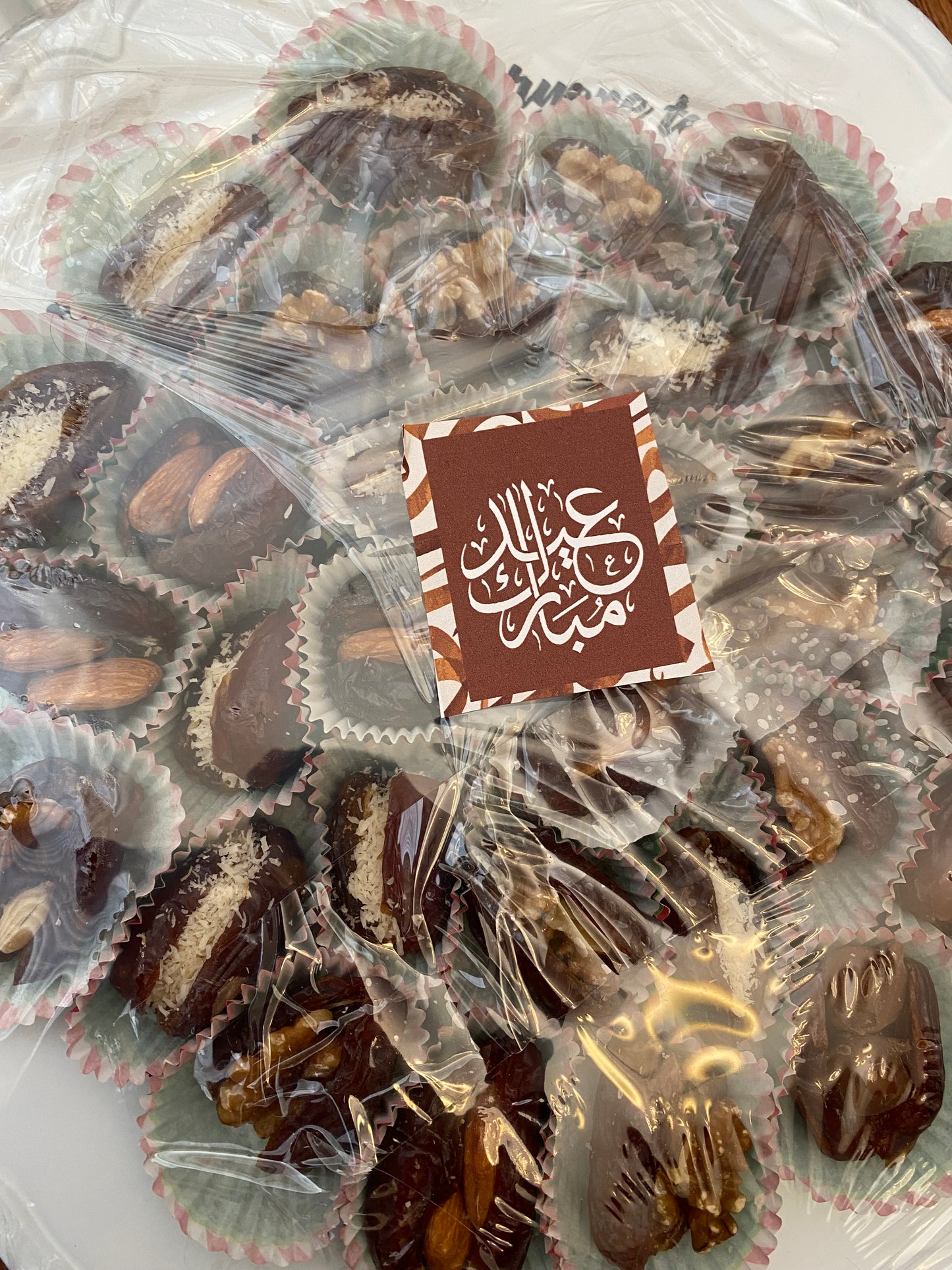 Assorted chocolates in clear wrappers on a white plate with a brand logo.