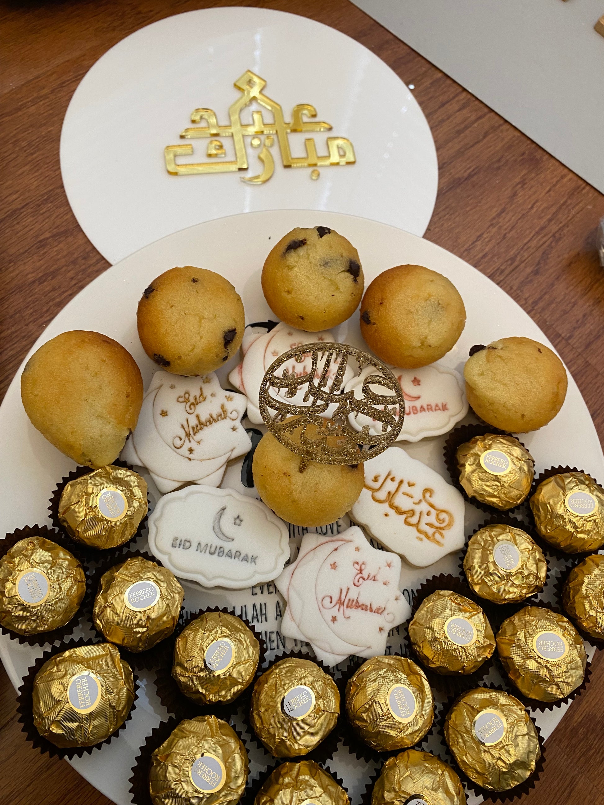 Assorted cookies and chocolates on a white plate with a wooden background