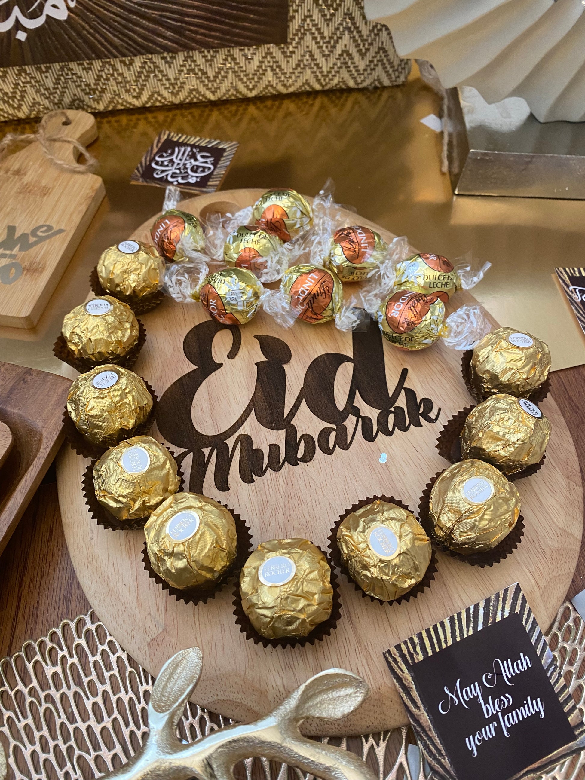 Ferrero Rocher chocolates on a decorative wooden board with a personalized card.